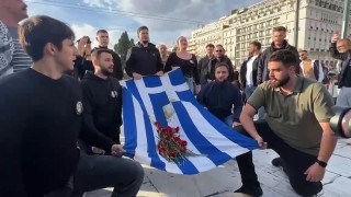 Διαδηλωτές ψέλνουν τον Εθνικό Ύμνο μπροστά από το μνημείο για τα θύματα των Τεμπών στο Σύνταγμα